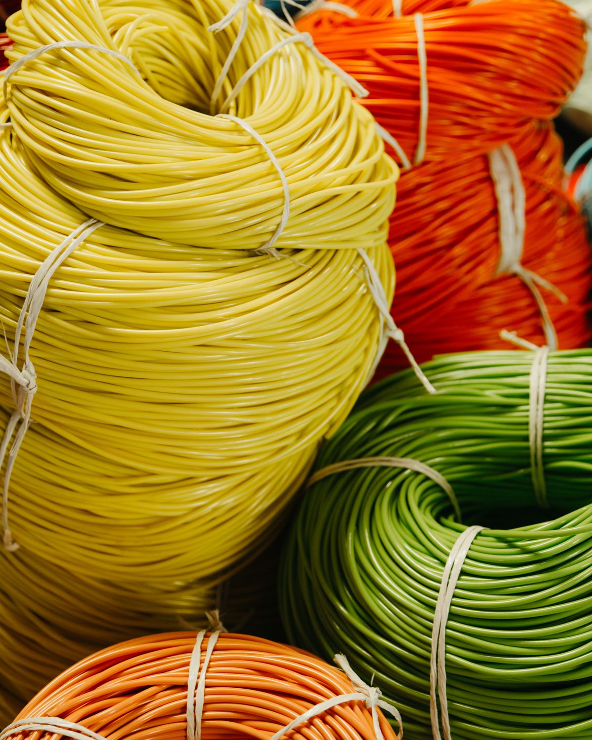 Rollos de cordón de PVC amarillo, naranja y verde, atados con cinta y vistos de cerca
