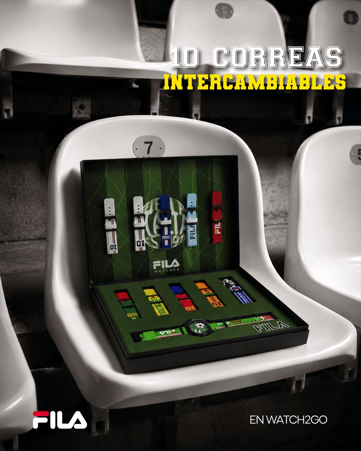 Estuche abierto de relojes FILA con un reloj de fútbol y diez correas de colores sobre fondo de cancha, puesto en una butaca blanca de estadio con el número 7; arriba, «10 correas intercambiables» y abajo, «En Watch2Go»